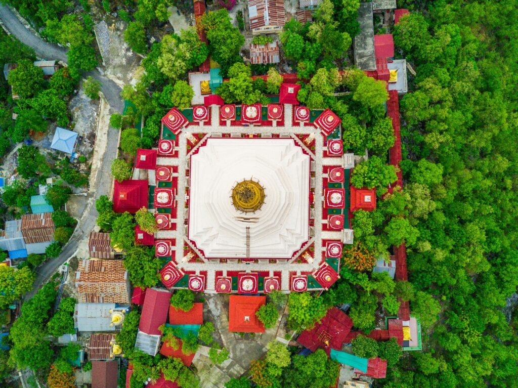 Stunning aerial shot of Mandalay's iconic pagoda surrounded by trees and vibrant architecture.